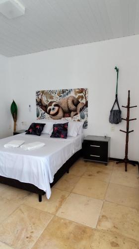 a bedroom with a bed with a painting on the wall at Pousada Preguiça in Canoa Quebrada