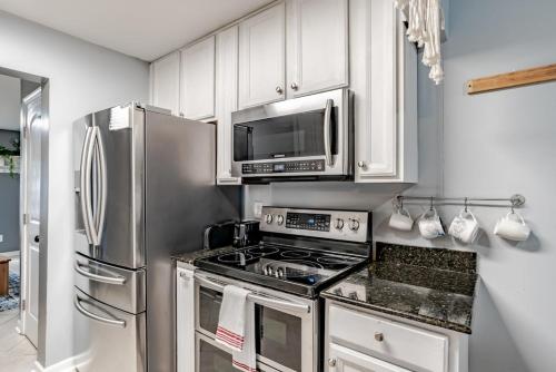 a kitchen with stainless steel appliances and white cabinets at Sunny Midtown Cottage- Midtown Mobile in Mobile