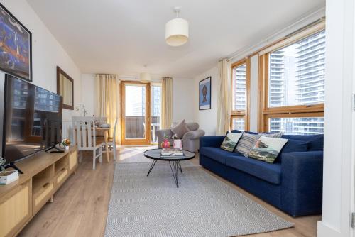 a living room with a blue couch and a tv at Luxury property with stunning views of Canary Warf in London