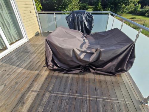 a covered chair on a deck on a house at HOLIDAY NEST Family Guest House 80m2 - Mysigt gästhus med två sovrum i Höör in Höör