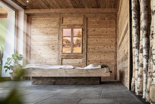 a wooden room with a bed and a window at Pension Aichner in Terento