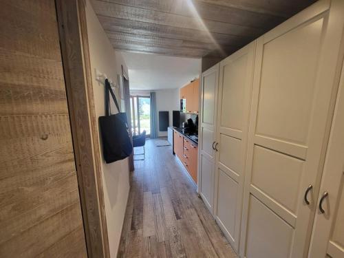 un couloir menant à une cuisine avec des armoires blanches dans l'établissement Studio moderne à Montgenèvre avec garage intégré - FR-1-266-245, à Montgenèvre