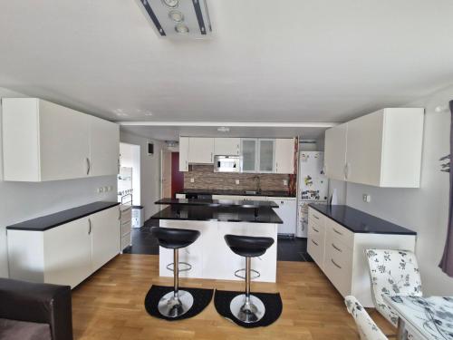 a kitchen with white cabinets and black counter stools at HOLIDAY NEST Family Guest House 80m2 - Mysigt gästhus med två sovrum i Höör in Höör