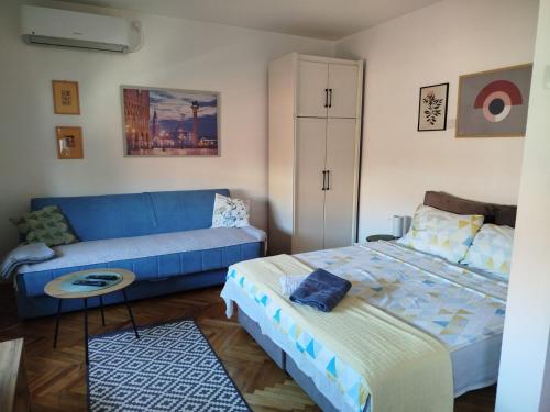 a bedroom with a blue bed and a couch at Fina Apartman in Leskovac