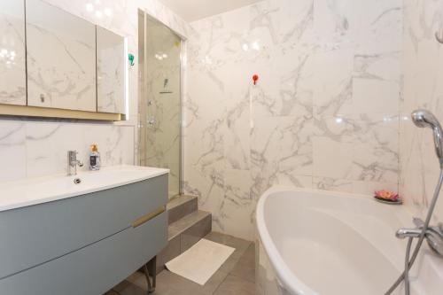 a white bathroom with a tub and a sink at Le Luma - Maison 6 prs - Jardin - Ping-Pong in Noisiel