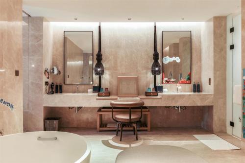a bathroom with a chair and a sink and a tub at Hilton Shanghai Songjiang Guangfulin in Songjiang