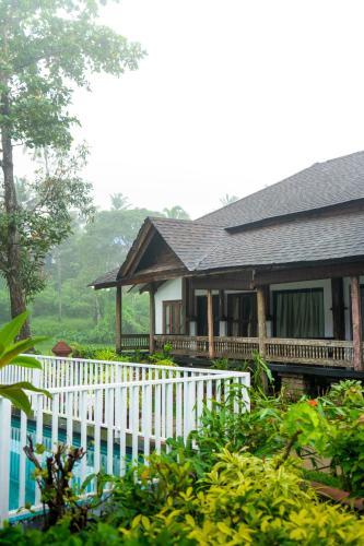 a house with a white fence in front of it at Palm TreeHeritage Beach Resort in Varkala