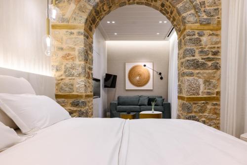 a bedroom with a white bed and a stone wall at STF Luxury Suites in Nafplio