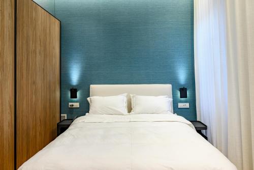 a bedroom with a white bed with a blue wall at STF Luxury Suites in Nafplio