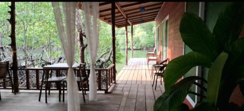 a porch of a house with tables and chairs at TA YAI HOMESTAY (ตา ยาย โฮมสเตย์) in Ko Kood