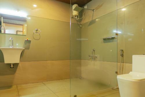 a bathroom with a shower and a toilet and a sink at Palm TreeHeritage Beach Resort in Varkala