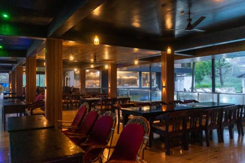 a dining room with tables and chairs and windows at Palm TreeHeritage Beach Resort in Varkala