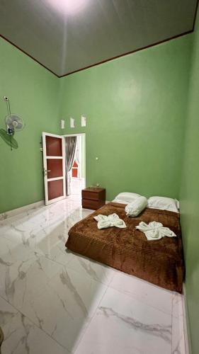 a bedroom with a large bed with green walls at NH Villa Lombok in Sangyang