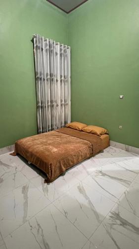a bed in a room with a green wall at NH Villa Lombok in Sangyang
