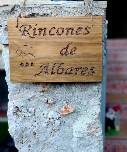 a wooden sign hanging on a stone wall with the words rhores de albers at Casa Rural Rincones de Albares in Albares