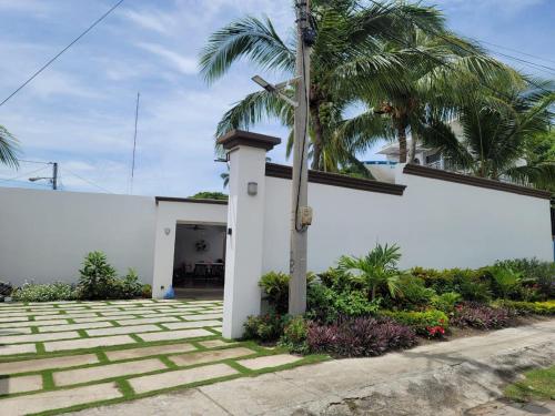 a white building with a palm tree in front of it at Lakefront Paradise Retreat, Private Pool Vacation Home in Rivas, between Ometepe, Tola and San Juan del Sur in San Jorge