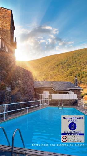 a swimming pool with a sign in front of a building at Égua Nature House in Piódão