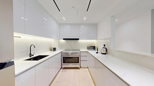 a white kitchen with a sink and a stove at Vacationer Holiday Homes I Stylish 2 Bed l Balcony with Pool Views l JVC in Dubai