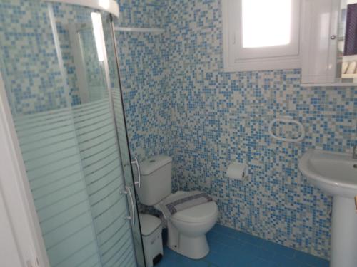 a blue tiled bathroom with a toilet and a sink at Blue and White Studios & Apartments in Lefkos Karpathou