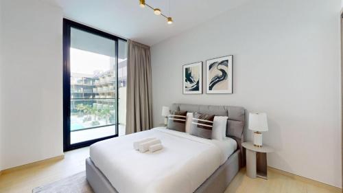 a white bedroom with a bed and a large window at Vacationer Holiday Homes I Stylish 2 Bed l Balcony with Pool Views l JVC in Dubai