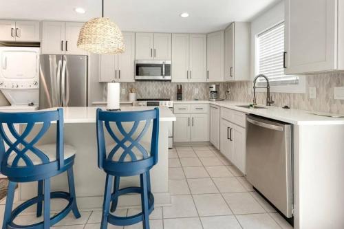 a kitchen with white cabinets and blue bar stools at The Retreat at Santa Rosa Beach Bungalow D in Destin