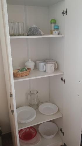 a white pantry with plates and bowls on shelves at Las Gemelas 3 - Villa Elisa in Villa Elisa