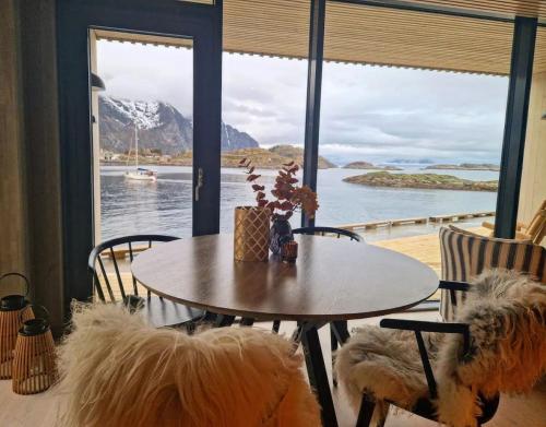 a table and chairs with a view of the water at Seafront apartment Henningsvær in Henningsvær