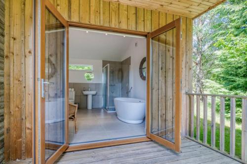eine Glastür, die zu einem Bad mit einer Badewanne führt in der Unterkunft Ben Lawers Rest Cabin - Hot Tub and Loch Tay Vistas in Lawers