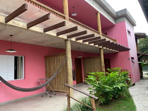 a pink house with a wooden staircase in front of it at Pousada Tubes Maresias in Maresias
