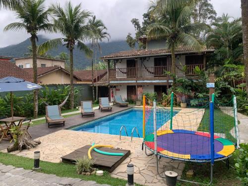 a house with a swimming pool with a playground at Pousada Tubes Maresias in Maresias