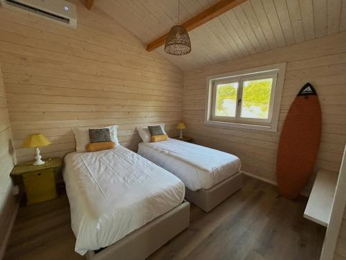 two beds in a room with wooden walls at Cabana in Sesimbra