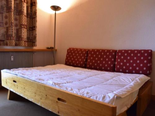 een slaapkamer met een houten bed en een rode bank bij Studio 2/4 pers, Accès Pistes et Piscine, Proche Commerces, Méribel - FR-1-180-297 in Méribel