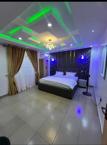 a bedroom with a bed with green lights on it at Vendes SERVICED APARTMENT in Alakuko