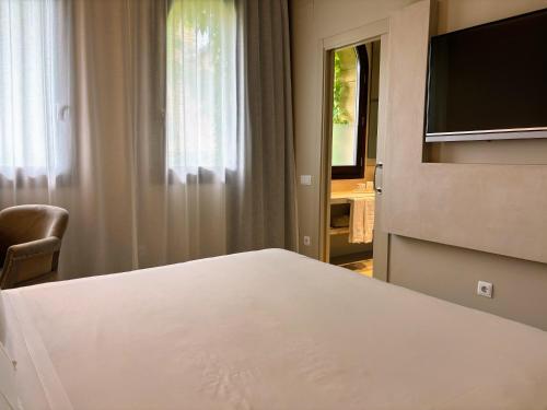 a bedroom with a white bed and a television at Les Clarisses Boutique Hotel in Vic