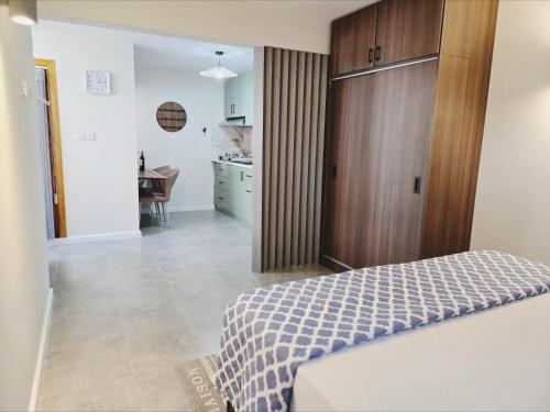 a bedroom with a bed with a wooden closet and a kitchen at Villa Soleil D’été in Blue Bay