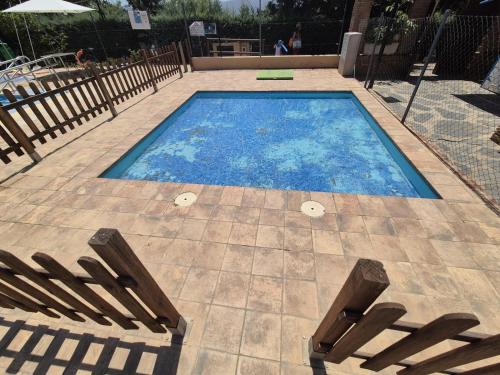 a large swimming pool with two benches in a patio at El Balcón de Ohanes R&R in Ohanes