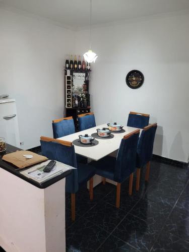 a dining room with a table and blue chairs at Linda casa para final de semana com churrasqueira in Praia Grande