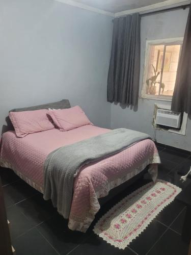 a bedroom with a bed with pink sheets and a window at Linda casa para final de semana com churrasqueira in Praia Grande