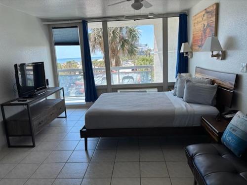 a bedroom with a bed and a tv and a couch at Georgian Inn Beach Club in Ormond Beach