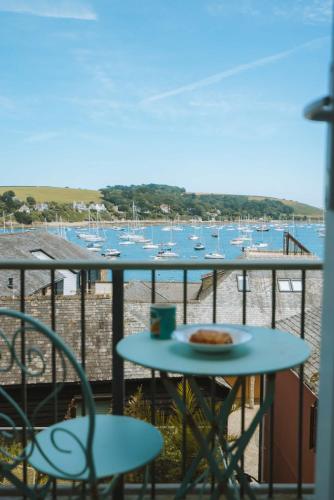 a table with a plate of pizza on a balcony with boats at Merthen House in Falmouth