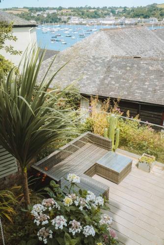 a deck with a bench and some flowers and boats at Merthen House in Falmouth