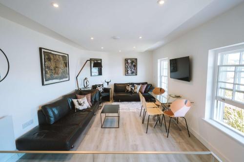 a living room with a black couch and a table at Merthen House in Falmouth