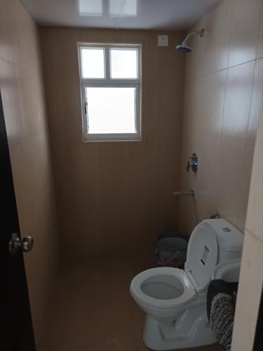 a bathroom with a toilet and a window at Skyview 3 bhk Retreat in Bayappanhalli