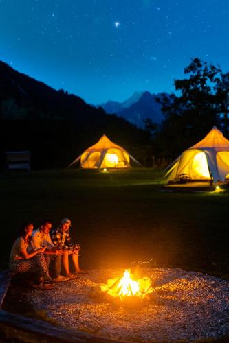 a group of people sitting around a fire in front of tents at Glamping Gozdna Jasa in Bovec