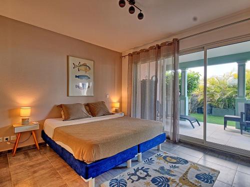 a bedroom with a bed and a sliding glass door at Appartement bord de mer avec climatisation, piscine et parking - FR-1-734-61 in Orient Bay