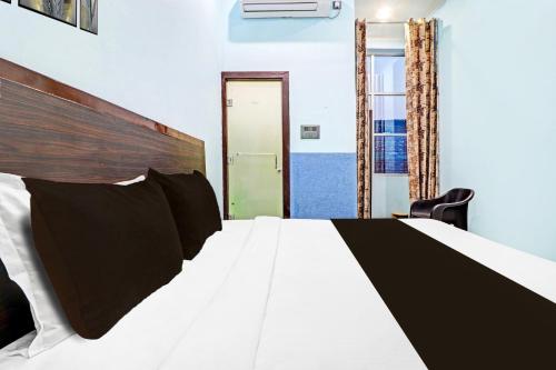 a bedroom with a bed with white sheets and black pillows at Hotel O Prakash Residency in Tapovan