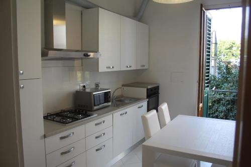 una cucina con mobili bianchi e un tavolo con un forno a microonde di Appartamento Rifredi a Firenze