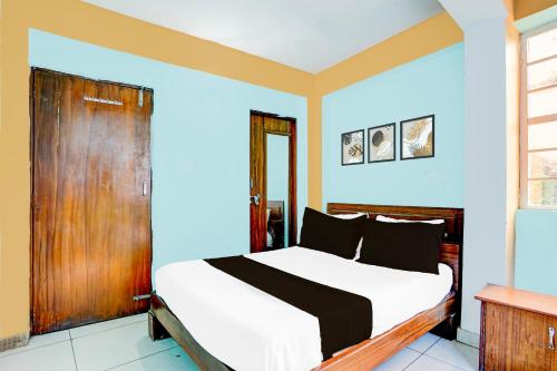 a bedroom with a bed with a wooden door at SPOT ON Hotel Heritage Inn in Rājpur