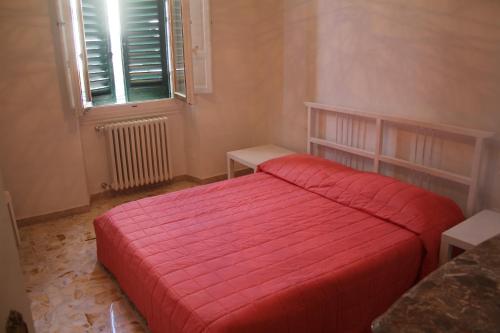 a bedroom with a red bed and a window at Appartamento Rifredi in Florence