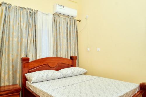 a bedroom with a bed and a window at Hopeland Apartments Limbe in Limbe